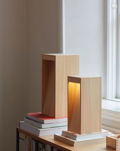 two wooden boxes sitting on top of a table next to a book shelf and window