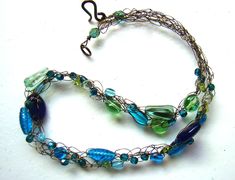 "This crochet wire necklace features beautiful Czech glass beads in a variety of shapes and sizes - all in shades of green, blue and teal. The beads are woven on bronze tone hypoallergenic wire and the necklace is finished with an easy to use artisan-made copper patina clasp. ElephantBeads crochet wire jewelry works well whether you're dressed up or dressed down in casual denim. Each piece can be gently manipulated to drape just right, and they are feather-light against the skin. Length: 17 inch Green Wire Wrapped Czech Glass Necklace, Green Wire Wrapped Beaded Necklaces With Round Beads, Green Wire Wrapped Czech Glass Beaded Necklaces, Green Wire Wrapped Beaded Necklace With Czech Glass, Green Glass Wire Wrapped Necklaces, Green Glass Wire Wrapped Necklace, Crochet Wire Jewelry, Wire Crochet Necklace, Teal Crochet