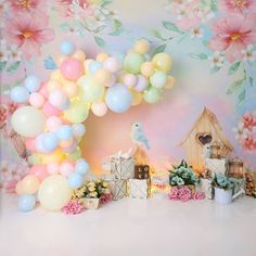 a backdrop with flowers and balloons in the shape of a bird on top of a house