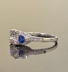 DeKara Designs Collection Beautiful Modern/Art Deco Diamond Blue Sapphire Pave Set Engagement Ring. Metal- 90% Platinum, 10% Iridium. Stones- 1 Genuine Round Diamond K-L Color VS1-VS2 Clarity 1.01 Carats, 96 Round Diamonds H-I Color SI1 Clarity 0.52 Carats, 2 Special Cut Trapezoid Blue Sapphires 0.40 Carats. Size- 6 1/2. FREE SIZING A Jaw Drop Gorgeous Art Deco Inspired Round Diamond Center Special Cut Blue Sapphire Diamond Engagement Ring Handmade in Platinum. There is a beautiful expertly pron Classic Sapphire Halo Ring With Brilliant Cut, Classic Sapphire Ring With Round Stone For Anniversary, White Sapphire Diamond Ring With Brilliant Cut, Timeless White Sapphire Ring With Round Cut, Classic Sapphire Ring For Anniversary, Classic Gia Certified Sapphire Ring In 14k White Gold, Brilliant Cut White Diamond Ring, White Sapphire Platinum Ring, Gia Certified Round Sapphire Ring