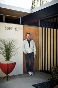 a man standing in front of a door next to a plant