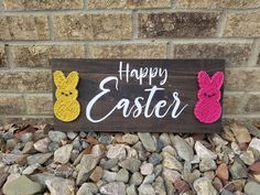 a wooden sign that says happy easter with two crocheted bunnies on it