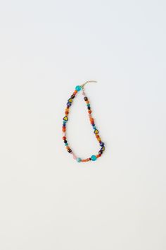 the multicolored beaded necklace is hanging from a hook on a white surface