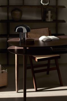 a wooden table with a book on top of it next to a chair and shelf