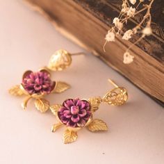 This lovely earrings are really cute, made of a resin handpainted purple-pink flower in a golden rose base. Gold plated filigree post earrings. Size from your piercing: 3.5 cms ( 1.30 Inches) Please note my jewelry is not waterproof, please avoid bathing and perfumes.  Please note the colors could vary slightly on each screen. If you have any question feel free to ask me! Your order comes in a gift box or a gift bag, so, it is ready for gift giving Thanks for looking! Unique Pink Flower Earrings As Gift, Unique Pink Flower Earrings For Gifts, Pink Pierced Earrings As Gift, Purple Earrings As Mother's Day Gift, Handmade Enamel Earrings For Wedding, Handmade Enamel Earrings For Party, Valentine's Day Gift Drop Clip-on Earrings, Pink Jewelry For Gifts, Pierced Ears, Handmade Drop Flower Earrings For Valentine's Day