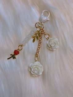 the key chain is decorated with white roses and a heart on it's side