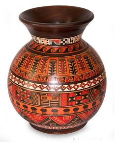 an orange and brown vase with designs on the bottom is sitting against a white background