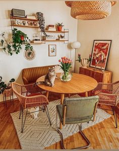 a cat sitting on top of a wooden table in a living room next to two chairs