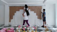 two people are standing in front of a backdrop with flowers and candles on the floor