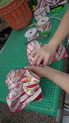 a person cutting paper with scissors on top of a green table next to potted plants