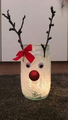 a glass jar with some branches sticking out of it and a red bow on top