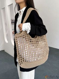 a woman carrying a crocheted bag in front of a white wall and grey floor