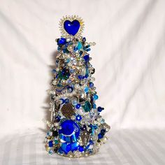 This Beautiful Costume Jewelry Tree Is A One Of A Kind, Hand Crafted Decorative Tree Using Jewelry Items That Might Otherwise Be Discarded. The Artist Has Spent Many Hours Lovingly Creating Something Beautiful For All To Enjoy. Many Colors Of Blue, Pearl And Silver. It Will Be The Stand Out Addition To Any Decor. It Measures 8 1/2" Tall X 4 1/2" Wide. The Stand And Glassware Shown Are For Display Purposes Only And Not Included In The Sale. Many More Crafted Trees Will Be Available In My Closet. Check My Listings For Additional Colors That Are Currently Available. Will Consider Requests For Custom Trees Through Poshmark Only. Tree Decor Christmas, Jeweled Christmas Trees, Jeweled Christmas, Cone Christmas Trees, Christmas Tree Art, Beautiful Costumes, Jewelry Tree, Blue Hand, Blue Pearl