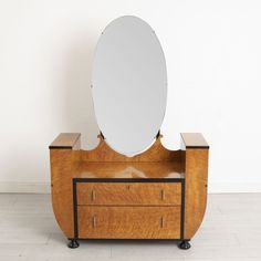 a mirror sitting on top of a wooden dresser next to a white wall and floor