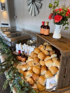 bread rolls piled on top of each other in a wooden crate with flowers next to it