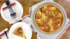 a pizza sitting on top of a wooden cutting board next to plates and utensils