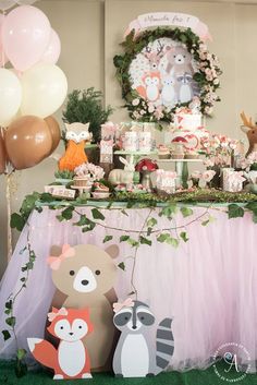 a table topped with lots of desserts and animals next to balloons in the air