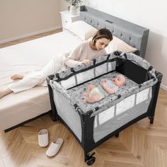 a woman laying on the floor next to a baby in a crib