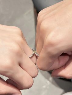 two hands touching each other with one holding the other's wedding ring in their left hand