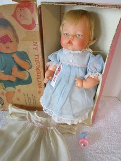 an old doll in a box next to a dress