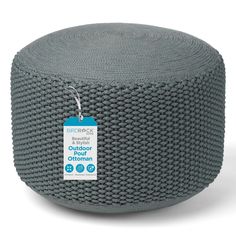 a round ottoman with a price tag on the front and back of it, in grey fabric