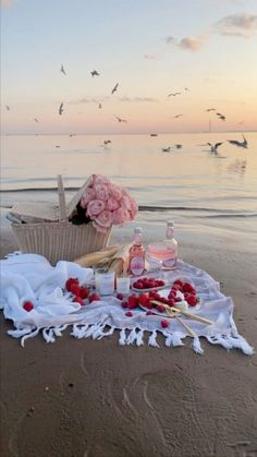 a picnic is set up on the beach with flowers and condiments in front of it