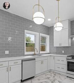 an empty kitchen with white cabinets and marble counter tops, along with two pendant lights