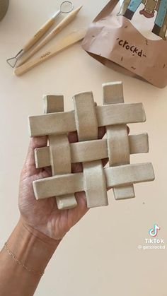 a person is making something out of clay on a white table with wooden utensils