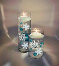 two candles are sitting next to each other with snowflakes on the candle holders