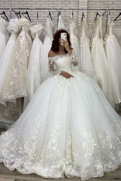 a woman is taking a selfie in front of wedding gowns on hangers