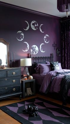 a bedroom decorated in purple and black with moon phases on the wall