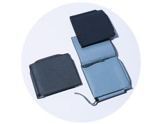 two wallets sitting next to each other on top of a white table with a black and blue one