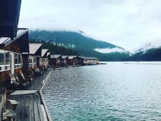 a row of houses sitting on the side of a body of water next to mountains