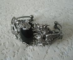 This beautiful silver plated filigree cuff bracelet has silver plated dragons, silver plated accents and a black onyx setting. Adjustable. Gothic Antique Silver Jewelry With Intricate Design, Medieval Style Silver Jewelry With Intricate Design, Gothic Silver Bracelet, Silver Gothic Bangle, Antique Silver Gothic Jewelry For Formal Occasions, Gothic Antique Silver Jewelry For Formal Occasions, Handmade Antique Silver Gothic Jewelry, Handmade Gothic Antique Silver Jewelry, Handmade Gothic Metal Bracelets