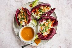 three lettuce wraps on a plate with dipping sauce