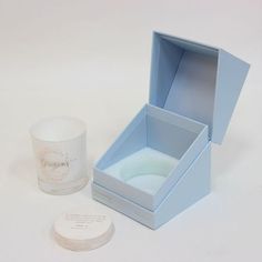 an open blue box next to a candle on a white surface with the lid opened