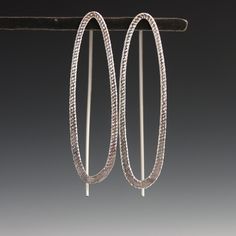 These earrings are curvy and sparkly with a decidedly modern edge - sure to please the art and design lover. The shimmering texture on the metal adds a little something unexpected, and is sure to draw lots of compliments. Featuring a narrow oval with subtle sparkle texture that catches the eye on the front, paired with a visible threader ear wire in the back, this design creates an intriguing and dimensional visual statement. 1.5" long with fixed wire threader ear wire. Available in sterling sil Modern Sterling Silver Oblong Earrings, Modern Oblong Sterling Silver Earrings, Modern Oval Link Metal Earrings, Modern Handmade Oblong Earrings, Minimalist Sterling Silver Oblong Earrings, Modern Oval Earrings With Ear Wire, Silver Oval Earrings For Everyday, Elegant Metal Oblong Earrings, Modern Oval Metal Earrings