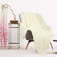 a living room with white walls and pink flowers on the side table next to a chair