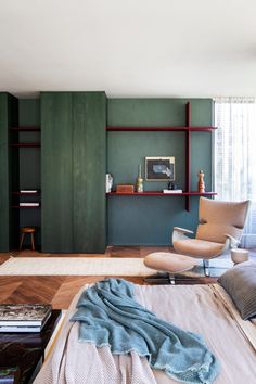 a bedroom with green walls and furniture in the corner, including a bed that has a blanket on top of it