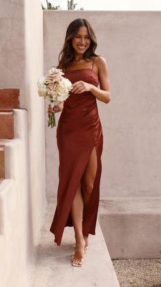 a woman in a red dress is holding a bouquet and walking up some steps with her feet on the ground