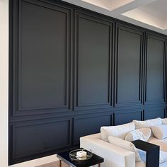 a living room filled with white furniture and walls painted in dark blue color palettes