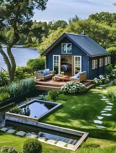 a small blue house sitting on top of a lush green field next to a lake