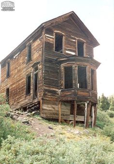 an old wooden house sitting on top of a hill