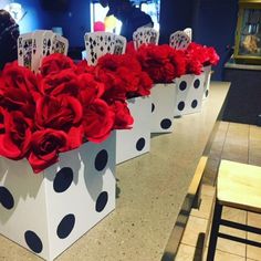 three white boxes filled with red flowers on top of a table