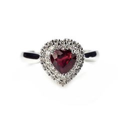 a heart shaped ring with diamonds on the sides and a red stone in the middle