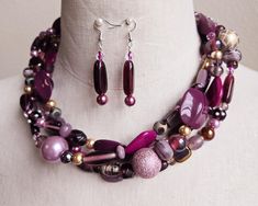 Make a real statement with this colorful necklace set. Glass lamp work beads, seed beads, freshwater pearls, Swarovski crystals, and resin beads in hues of mauve, burgandy,  purple, lavender, and gold are strung onto 4 wires.  I finished the design with decorative silver bead caps and a large lobster clasp.  The necklace measures 20 inches long.  Matching beaded drop earrings are hung on 925 silver ear wires. Multi-strand Czech Glass Jewelry With Large Beads, Czech Glass Large Beads Multi-strand Jewelry, Costume Jewelry With Large Beads And Multi-strand, Unique Multi-strand Jewelry With Spacer Beads, Multi-strand Large Bead Party Jewelry, Purple Faceted Beads Jewelry For Party, Purple Jewelry With Faceted Beads For Party, Purple Round Beads Jewelry For Party, Multi-strand Polished Beads Jewelry For Parties