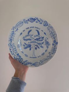 a hand holding a blue and white plate with an image of a tree on it