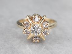 a yellow gold engagement ring with diamonds on the top and bottom, sitting on a white surface