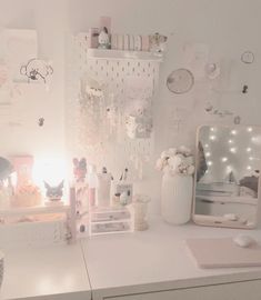 a white desk topped with lots of clutter next to a wall mounted clock and mirror