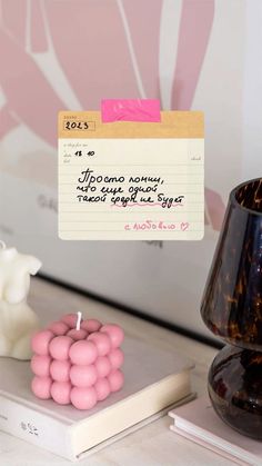 there is a note pinned to the wall next to a candle and some pink balls